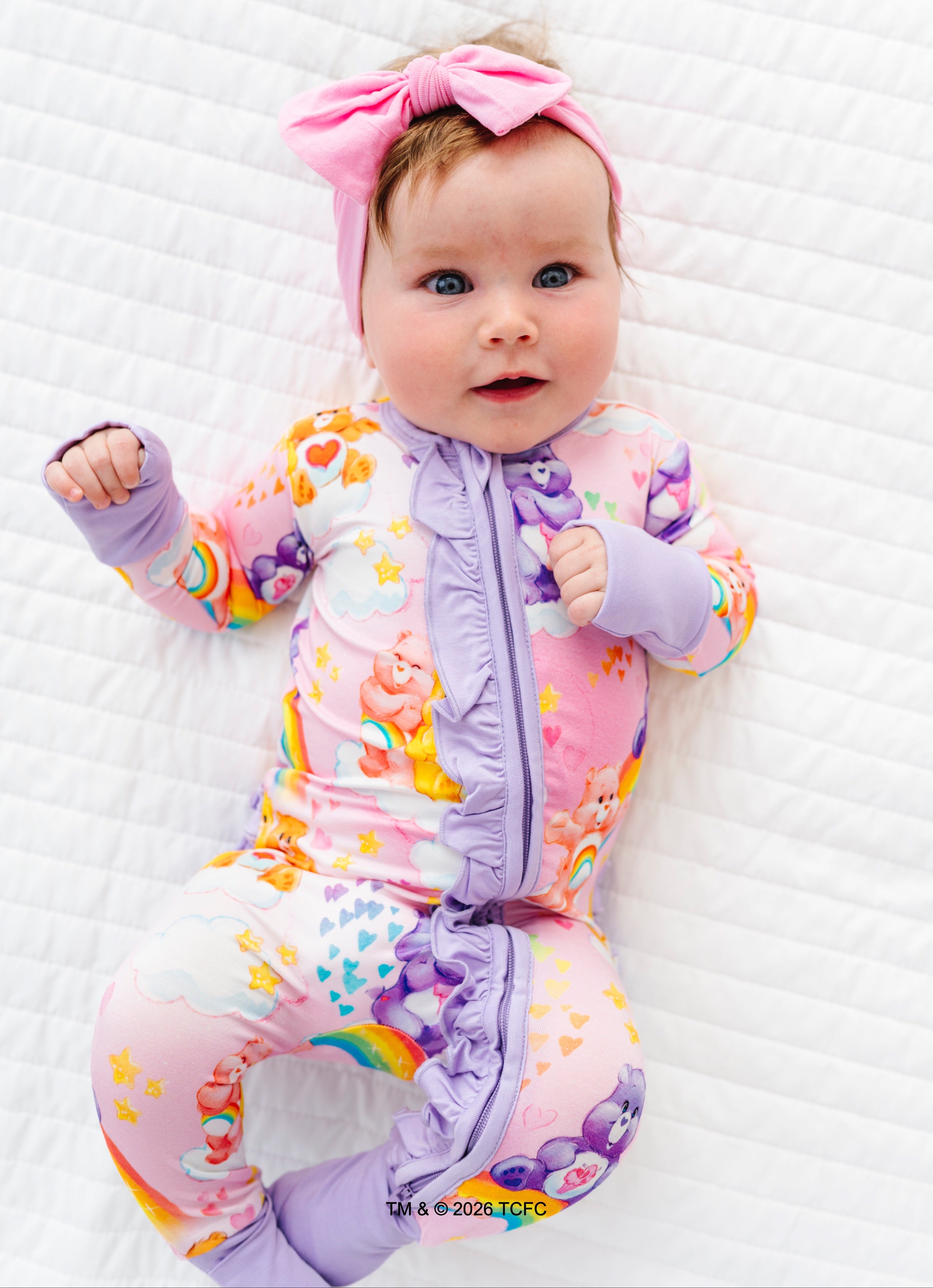 Baby wearing a bamboo Care Bears™ convertible romper with rainbow patterns on a white background